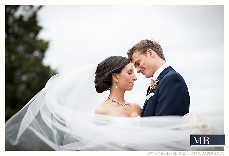 bride and groom smiling with long flowing veil